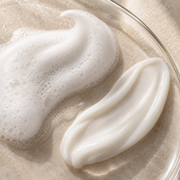 Creamy shampoo texture with water droplets on warm stone
